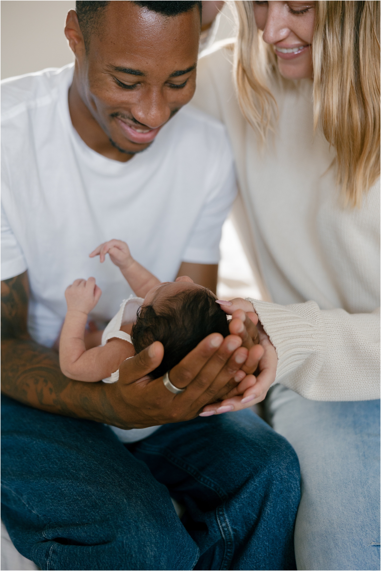 Smiling parents gently holding their newborn baby together